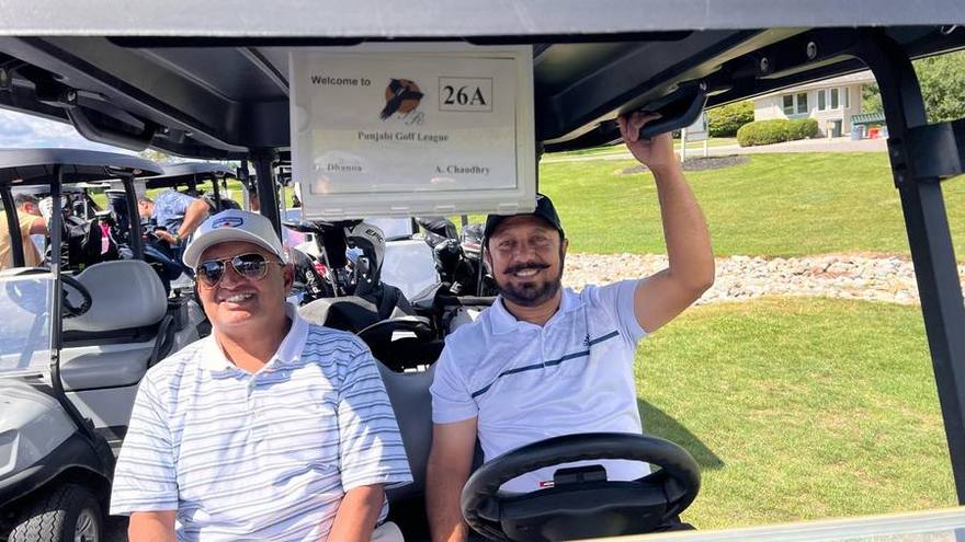Two golfers in a cart with a Punjabi Golf League scorecard reading 26A on the windshield
