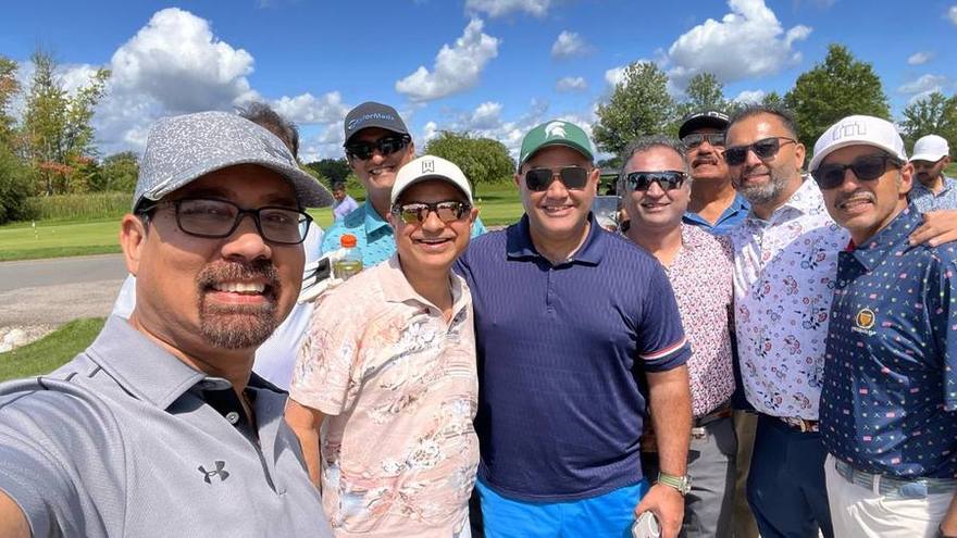 A group of golfers gathered together on the course under a blue sky